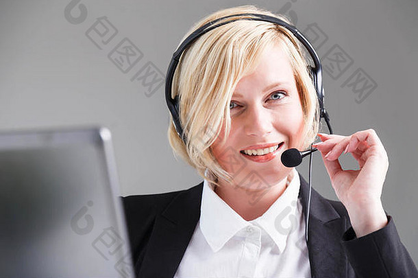 微笑女人调用中心操作符穿着黑色的时尚的西装耳机耳机
