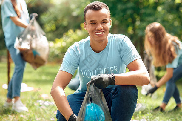 志愿服务年轻的人志愿者在户外非洲男孩特写镜头挑选垃圾塑料袋微笑快乐的模糊背景