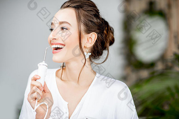 肖像美丽的女人闪亮的微笑持有冲洗器工具牙齿清洁浴室