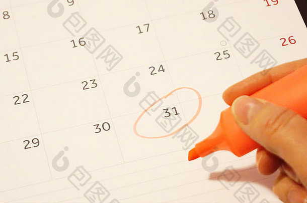 女手持有橙色标记笔环绕31日一天日历表结束一年一年未来概念