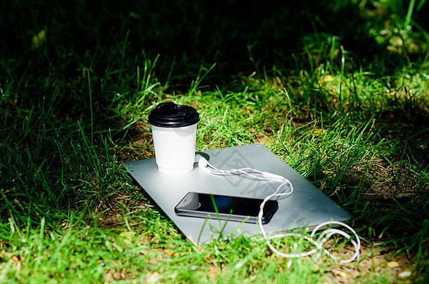 远程工作咖啡打破在户外夏天假期工作放松自然环境咖啡时间咖啡移动PC现代智能手机耳机咖啡杯绿色草