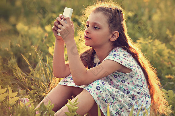 可爱的孩子女孩坐着玻璃玩移动电话脸夏天背景健美的肖像