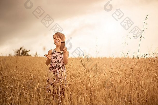 女孩智能手机同时笑小麦场