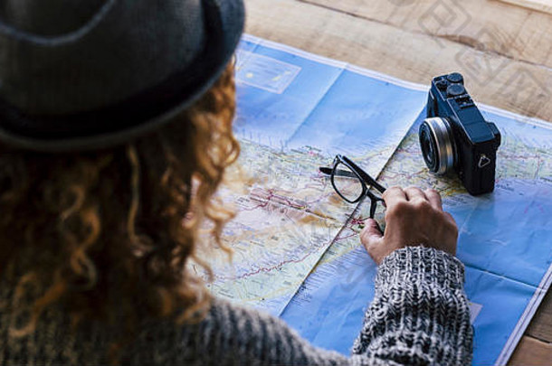赶时髦的人卷曲的金发女郎女查看后规划旅行假期旅游热地图眼镜相机木表格全球在世界范围内球选择梦想目的地