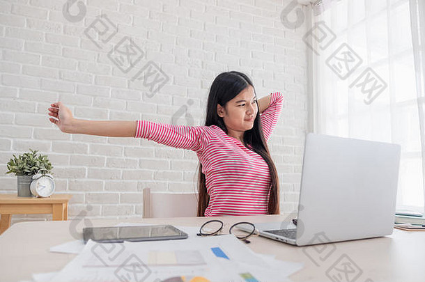 亚洲女人伸展运动手臂工作移动PC白色砖墙首页工作首页概念放松硬工作