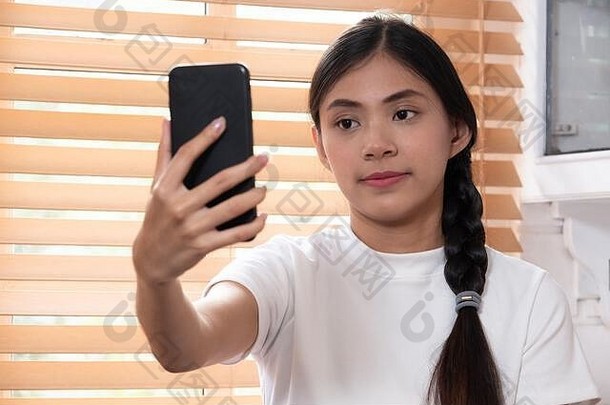 年轻的亚洲女人使视频调用智能手机首页