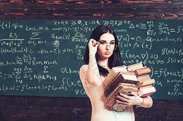 浅黑肤色的女人学生粉红色的开襟羊毛衫持有眼镜美丽的大学女孩携带桩重书