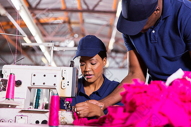 纺织工厂工头帮助年轻的<strong>缝纫</strong>机械师服装工厂