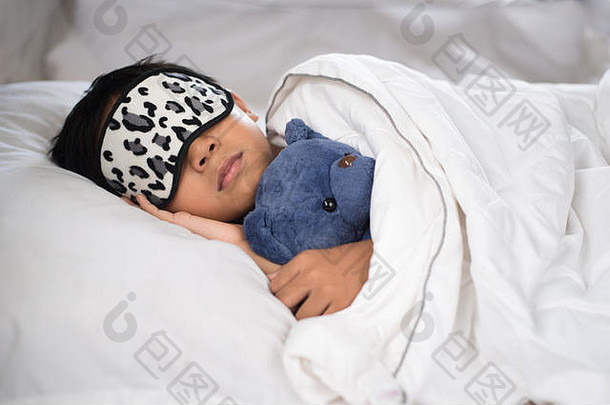 男孩睡觉床上泰迪熊白色枕头表穿睡眠面具男孩秋天睡着了早....睡眠概念