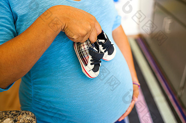 怀孕了拉美裔女人持有婴儿鞋子