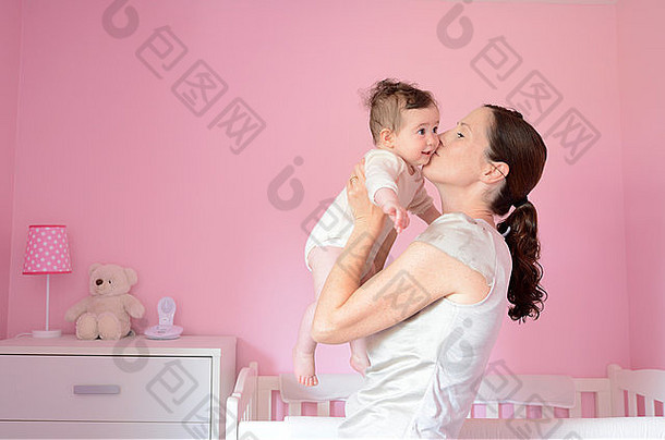 年轻的妈妈。吻婴儿女孩年龄个月概念照片为人父母母亲