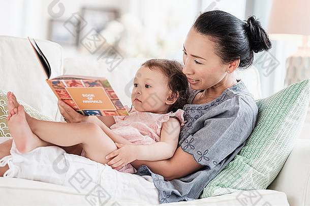 妈妈。婴儿女儿阅读沙发