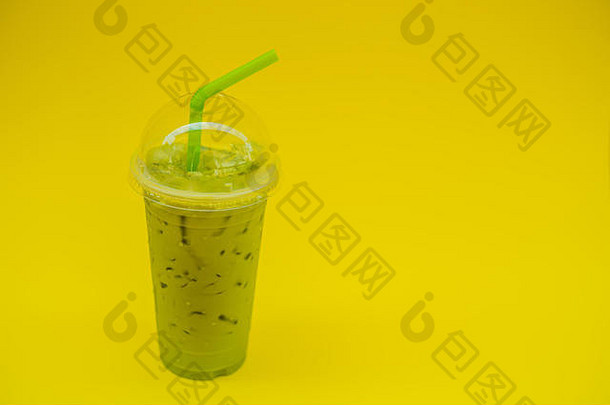 绿色茶拿铁冰塑料杯稻草女手黄色的修指甲黄色的背景自制的冰火柴拿铁茶牛奶