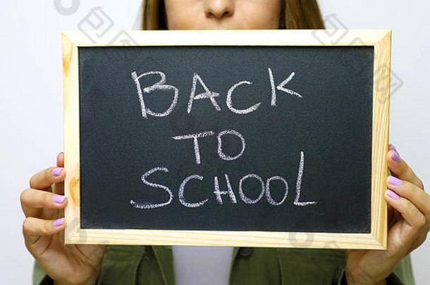 回来学校年轻的女人持有黑板上写作回来学校焦点黑板上
