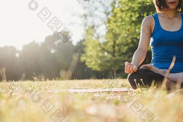 成熟的女人公园坐着瑜伽位置低角视图