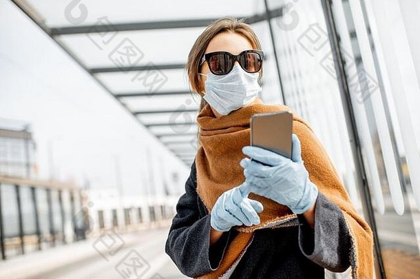 年轻的女人脸面具医疗手套太阳镜聪明的电话公共运输停止疫情概念社会距离在线沟通