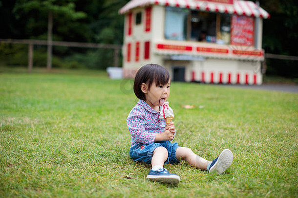 婴儿女孩坐着夏天草地吃冰淇淋