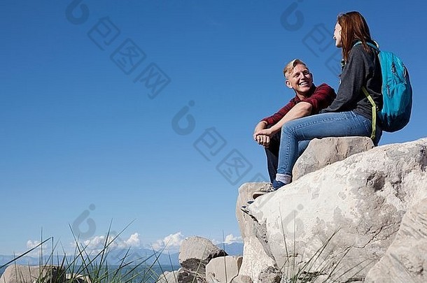 低角视图年轻的夫妇坐着岩石微笑