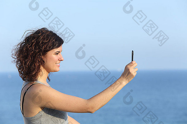 女人使照片移动电话海背景