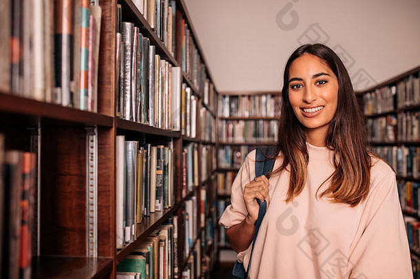 年轻的学生站图书馆肖像快乐年轻的女人袋站公共图书馆书架