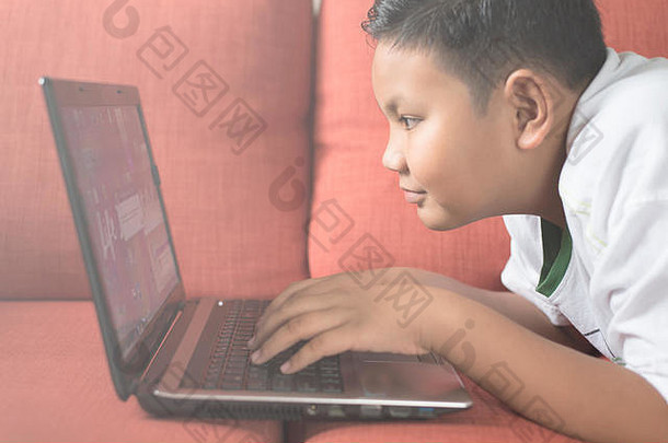 年轻的亚洲男孩移动PC电脑沙发首页男孩放松沙发首页技术概念电脑学习概念
