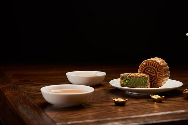 传统的中国人月饼杯茶黄金锭孤立的黑色的