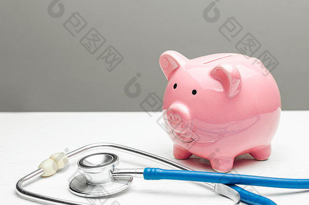 粉红色的小猪银行听诊器灰色的背景概念保存健康保险个人保险