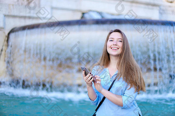 年轻的高加索人学生聊天智能手机特莱维喷泉背景