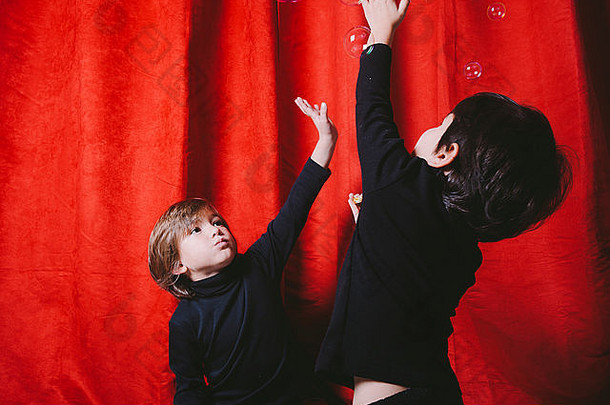 男孩穿黑色的衣服玩汤泡沫红色的窗帘