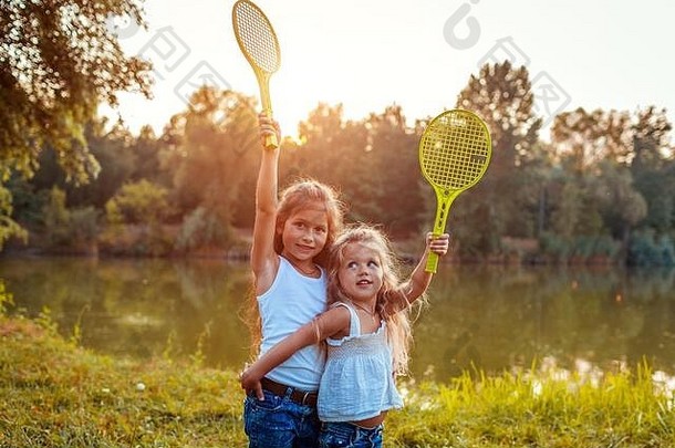 女孩有趣的在户外玩羽毛球姐妹提高球拍春天公园孩子们活动