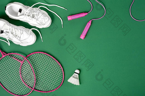 体育设备羽毛球羽毛球球拍跳过绳子运动鞋绿色背景健身体育运动健康的生活方式概念