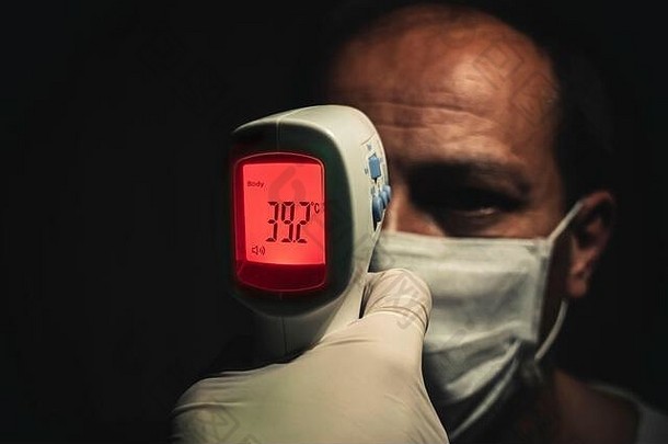 特写镜头拍摄红外温度计测量高级男人的危险的高身体温度发热