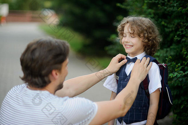 父亲伴随son-grader学校坐男孩小心翼翼地整理了一下弓领带儿子关闭