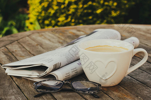 报纸阅读眼镜杯咖啡木表格在户外