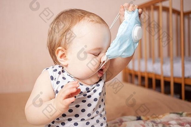孩子穿医疗面具一年女孩米色背景需要蓝色的呼吸器空空间文本孩子