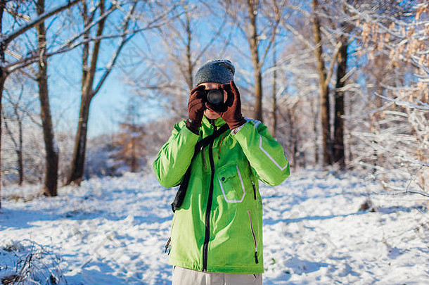 年轻的摄影师需要图片冬天森林相机年轻的男人。拍摄照片在户外