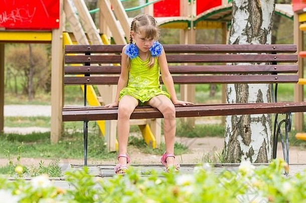 哭女孩坐着板凳上背景操场上