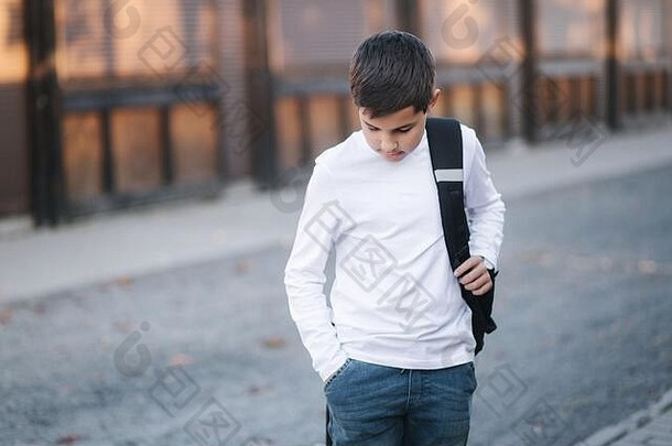 十几岁的男孩无线耳机把耳朵年轻的男孩白色衬衫背包男孩听音乐