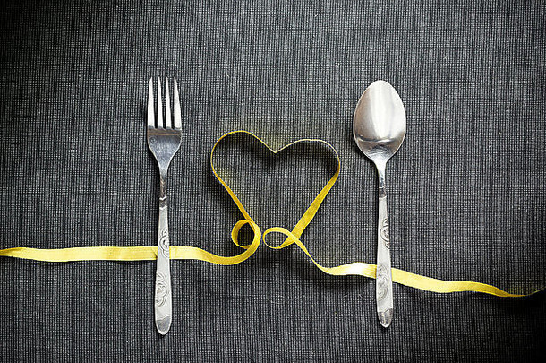 叉勺子心形状使黄色的丝带黑色的变形背景