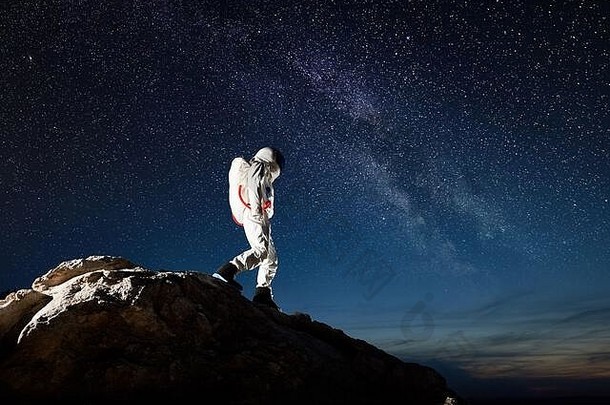 宇航员走岩石山神奇的晚上天空星星宇航员空间西装探索表面地球概念星系乳白色的空间旅行