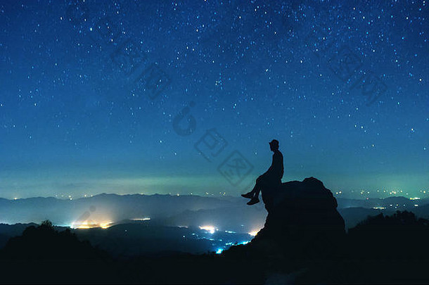 男人。坐在大岩石晚上天空背景