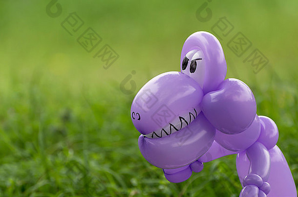 特写镜头紫色的<strong>气球</strong>动物<strong>恐龙</strong>牙齿眼睛可怕的郁郁葱葱的绿色草回来院子里