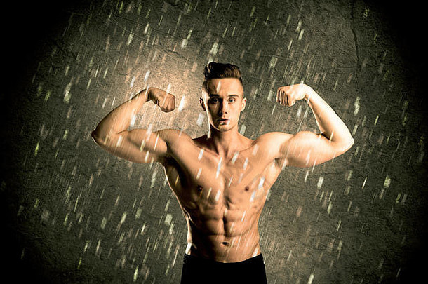 英俊的年轻的身体构建器举重显示肌肉发达的上身体雨概念