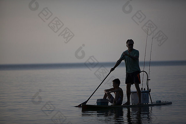 的轮廓男人。十几岁的儿子钓鱼paddleboard湖优越的火车湾密歇根美国