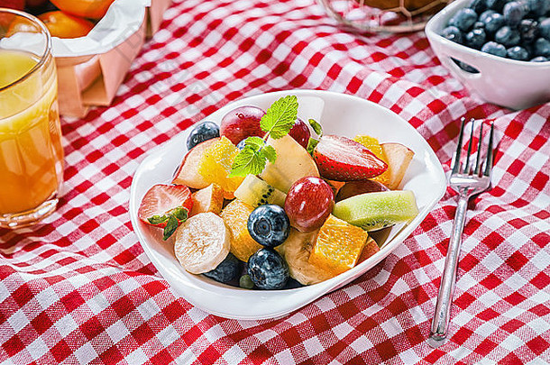 健康的夏天野餐新鲜的色彩斑斓的热带水果沙拉服务碗红色的白色检查布