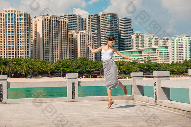 快乐的美丽的女孩有趣的假期跳码头背景城市中国海南城市<strong>三亚</strong>视图岛湾