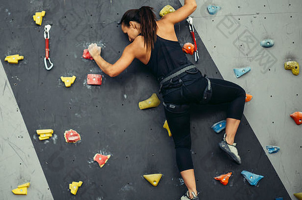 后视图unrecogizable女人练习岩石攀爬人工岩石健身中心活跃的生活方式抱石概念