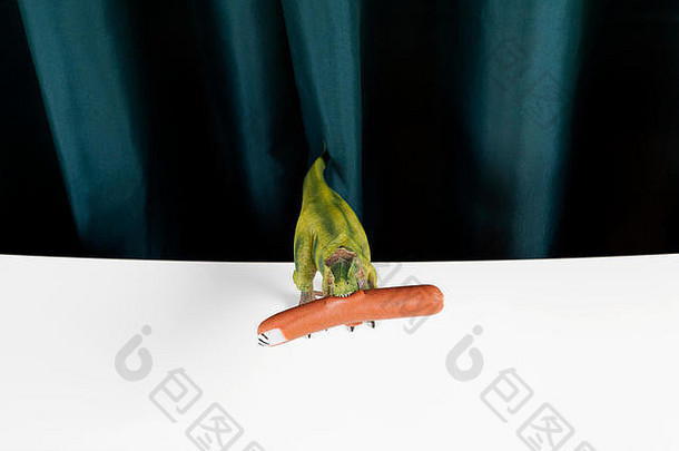 塑料玩具暴龙雷克斯吃香肠假指甲象征着手指充满活力的绿色窗帘白色背景最小的有趣的