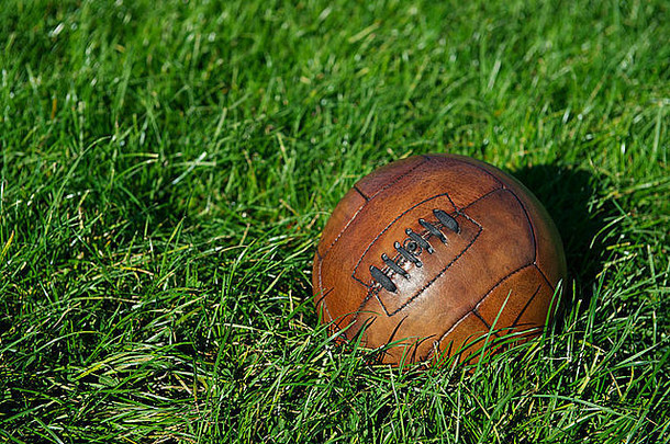 古董棕色（的）足球足球球坐在阳光明媚的绿色草场