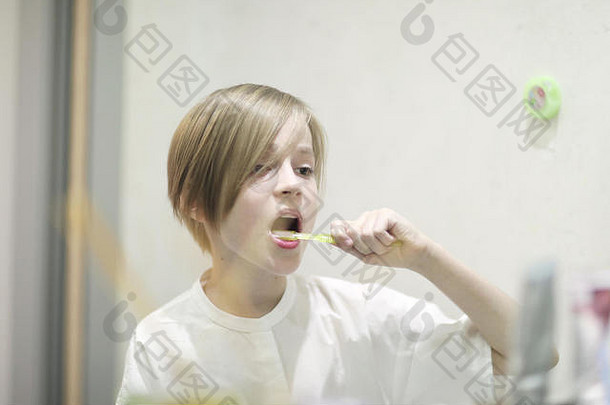 学龄男孩时尚的发型刷牙齿前面镜子牙医的办公室
